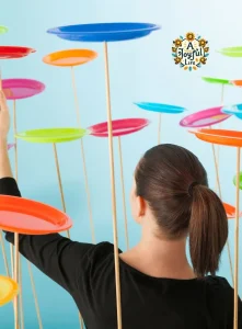 A woman seen from behind balancing multiple colorful spinning plates on sticks, symbolizing multitasking or managing many responsibilities at once.