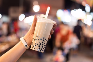 A hand holding a milk tea with tapioca pearls.
