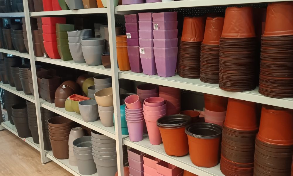 Shelves neatly stocked with colorful plant pots and gardening containers arranged by size and color, representing organization and why simplicity matters in both life and business.