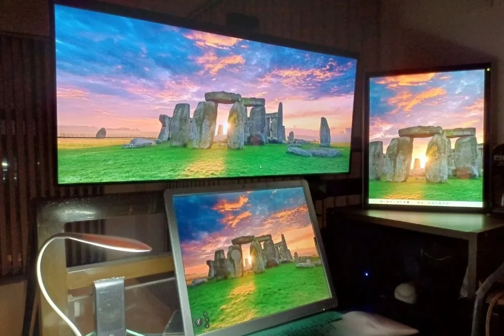 Home office setup with three computer monitors displaying a scenic landscape wallpaper, representing the belief that meaningful living and business both start at home.
