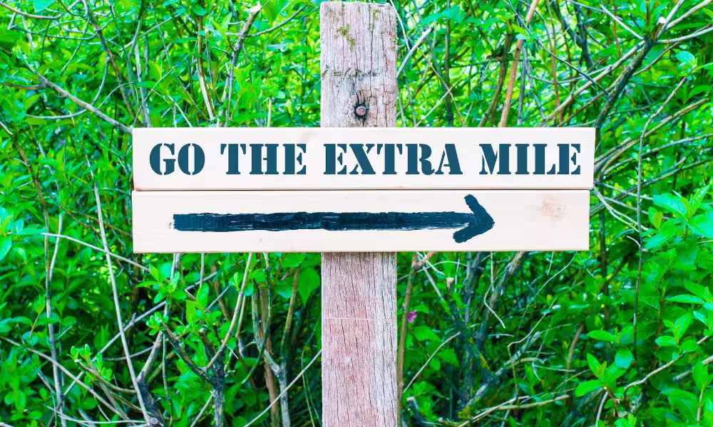 A sign saying Go The Extra Mile with an arrow going forward.