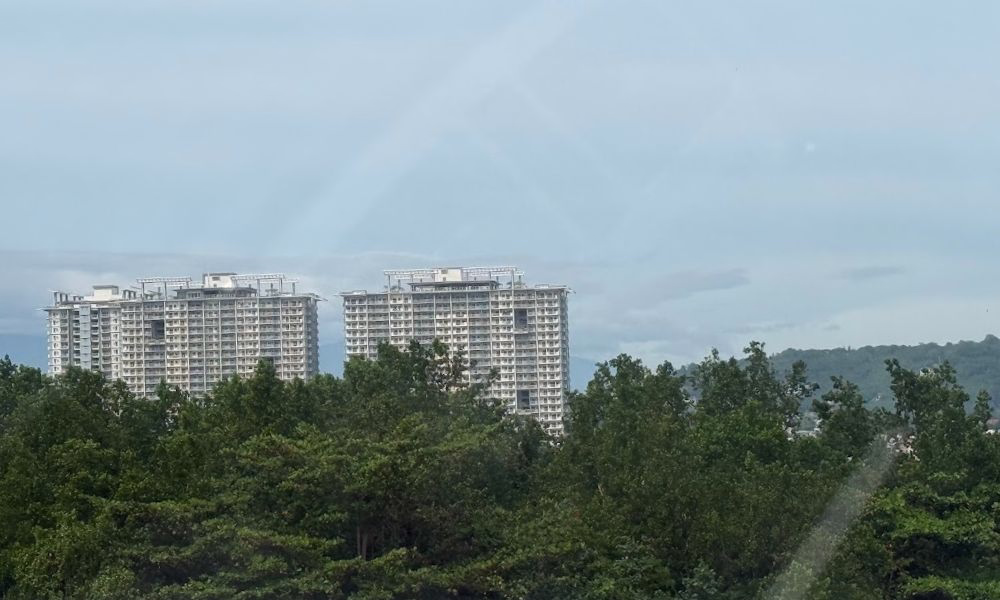 Two buildings standing tall over lush trees in Davao City.